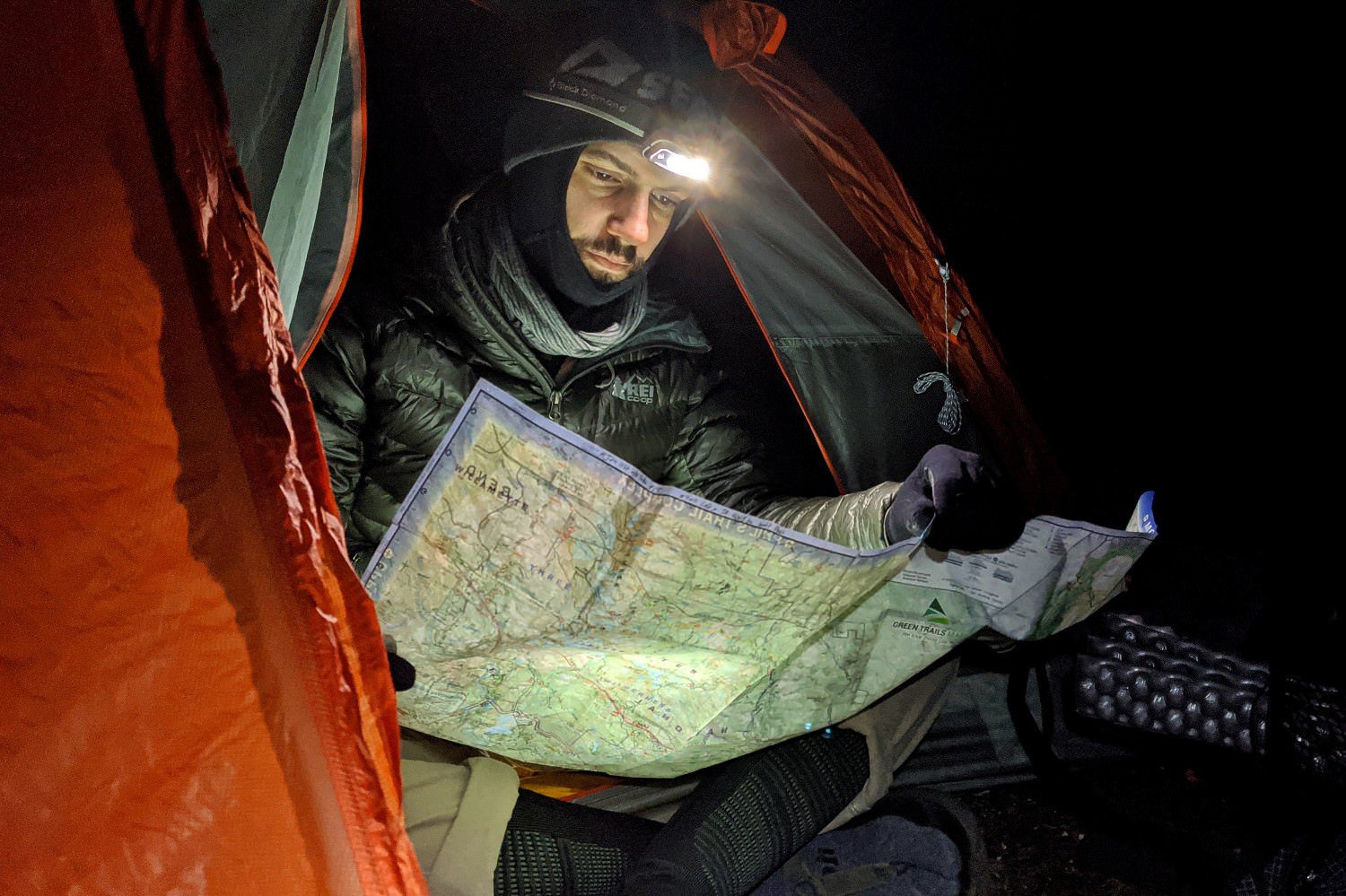 A backpacker reading a map of the Three Sisters with a headlamp