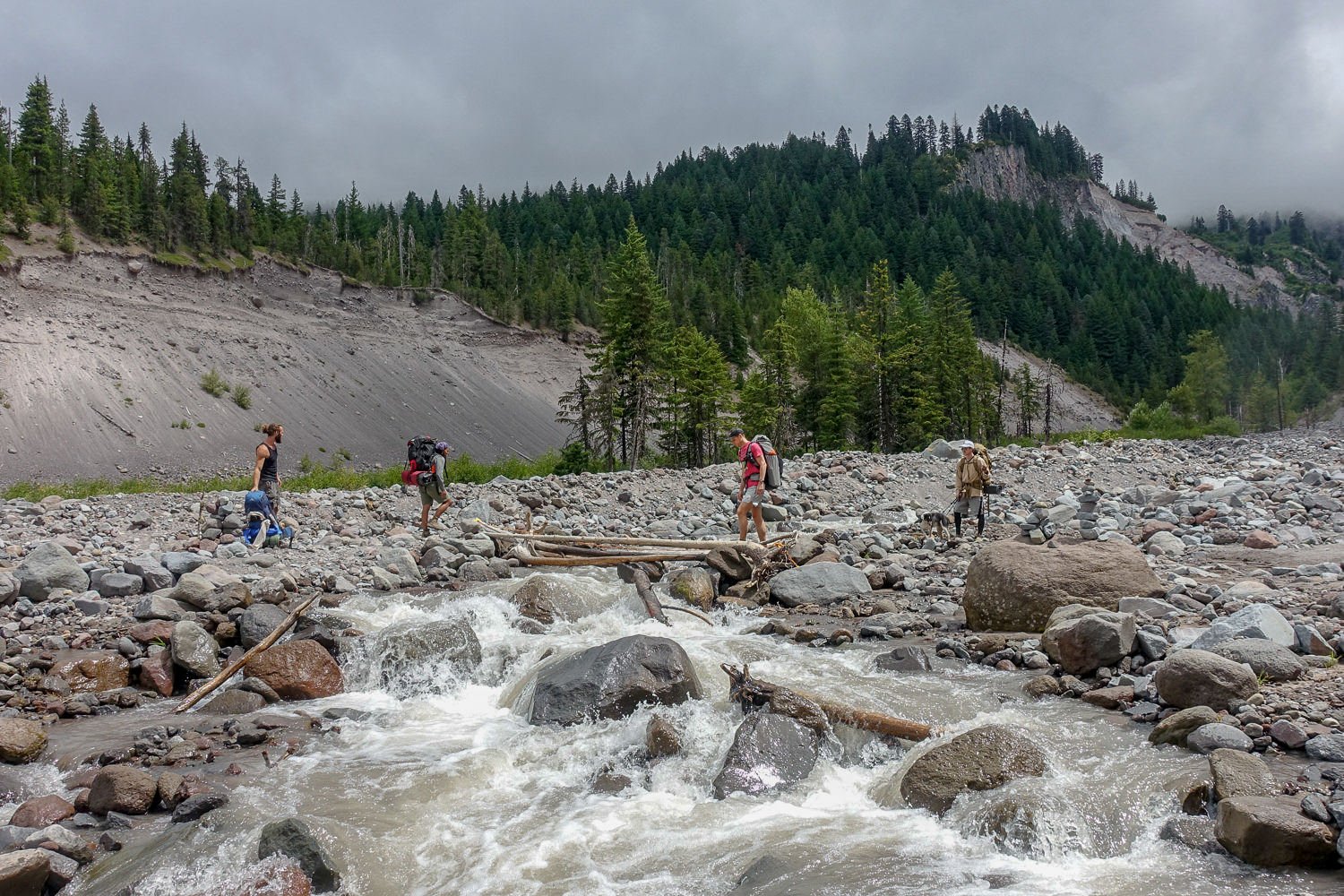 Backpackers fording a river on the Timberline Trail.