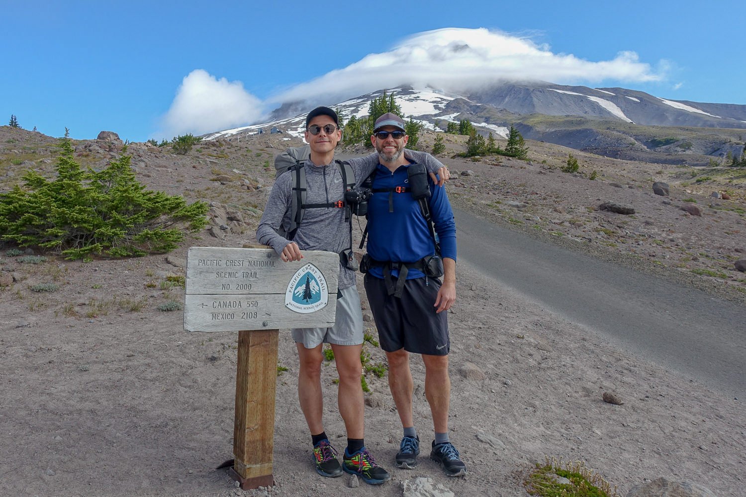 Two backpackers posing at the start of their trek on the Timberline Trail.