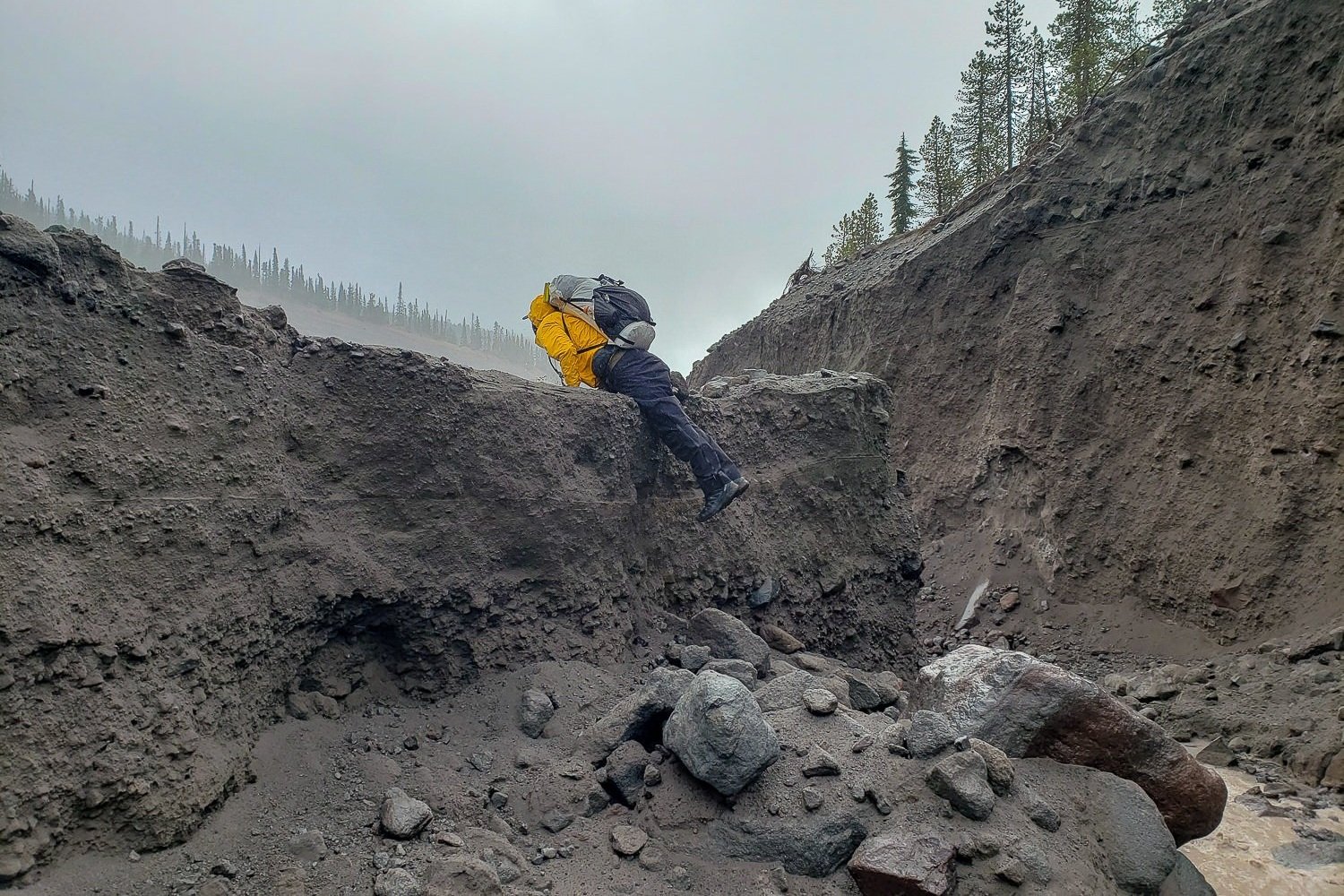 A backpacker climbing up a steep sandy creekbed on the Timberline Trail in October