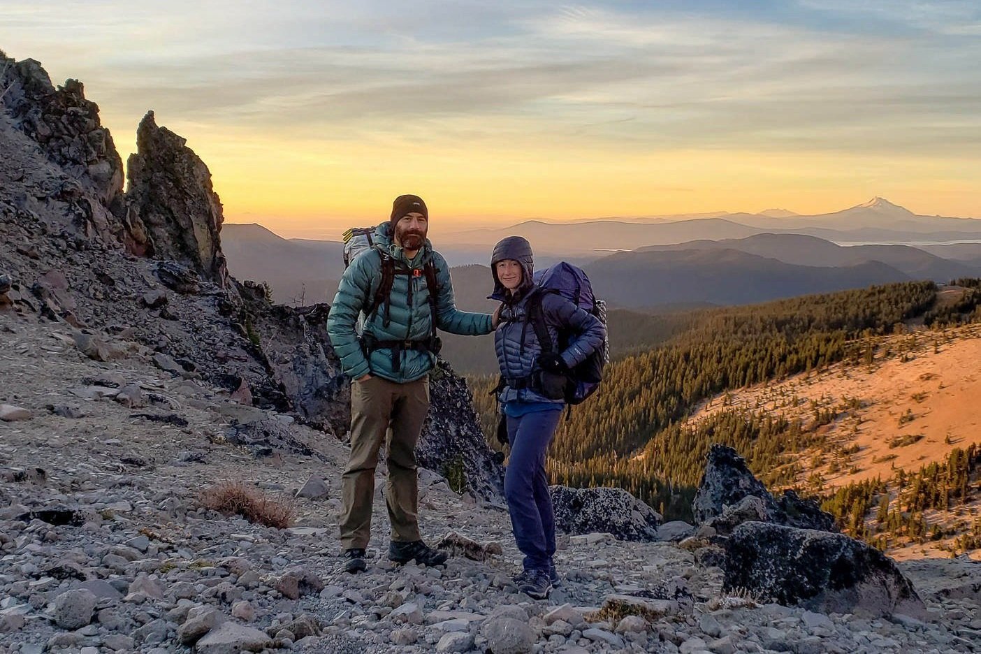 A backpacker couple posing for a photo at sunrise near Gnarl Ridge on the Timberline Trail