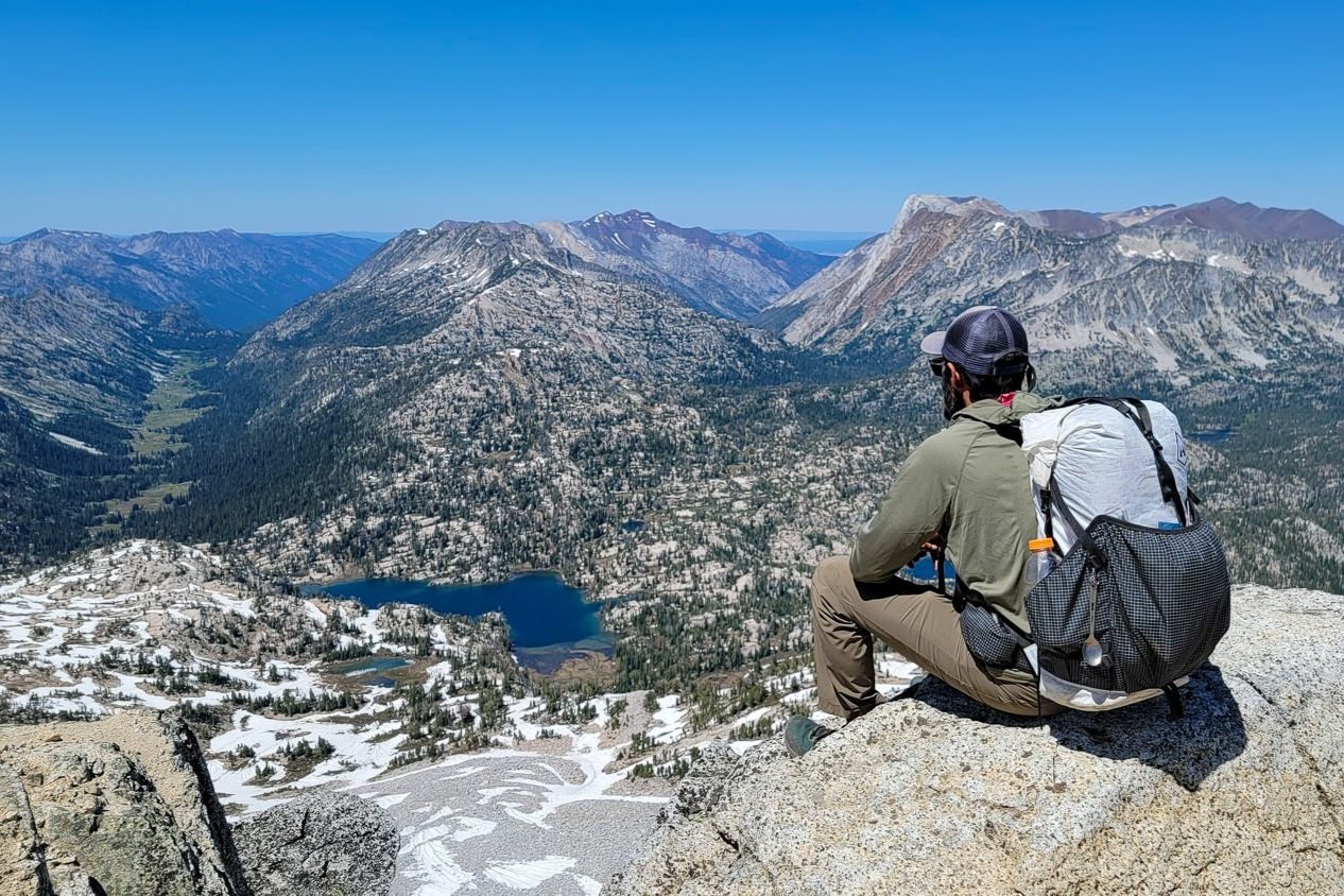 A backpacker looking out over the Wallowas from the summit of Eagle Cap Mountain.