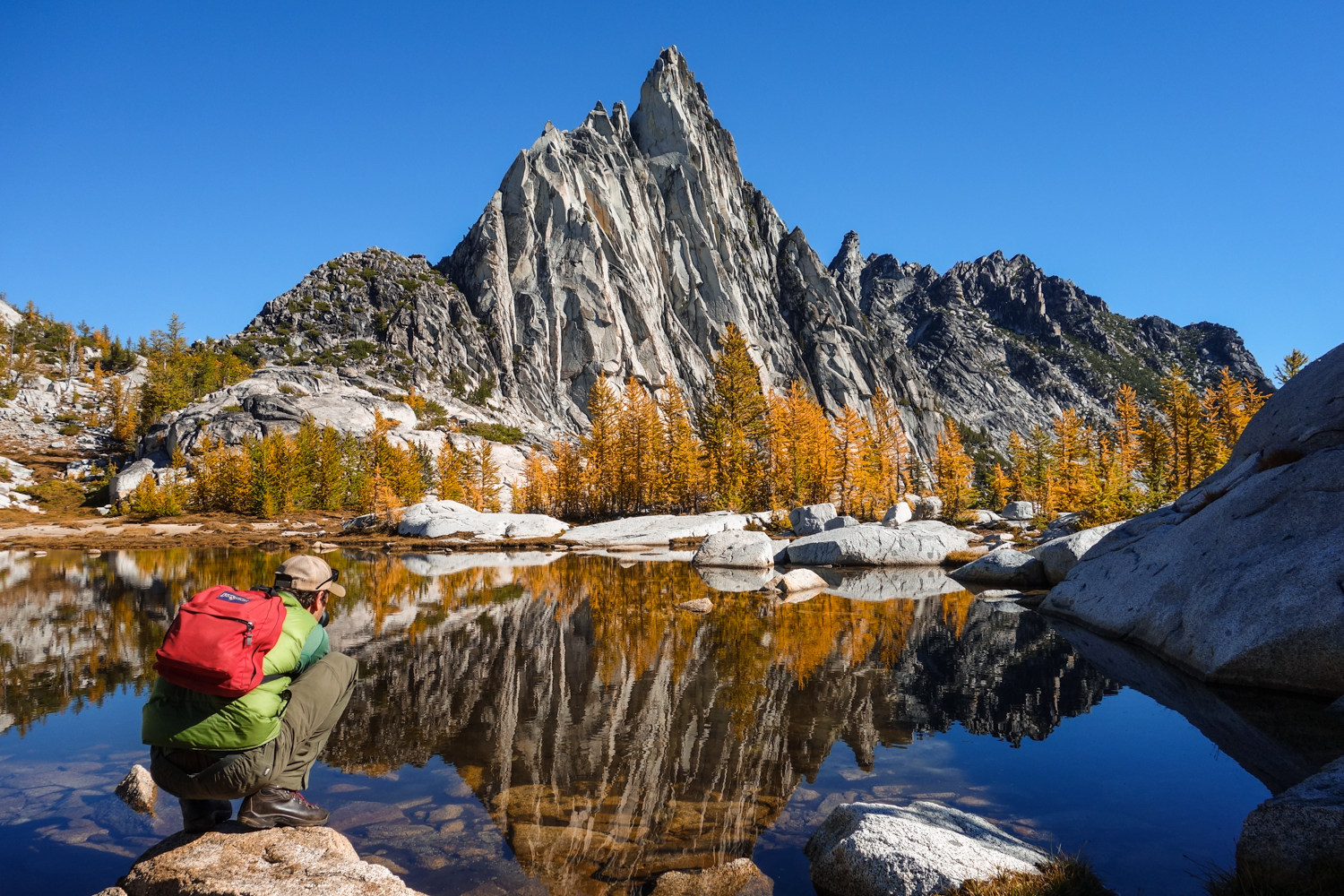 prussik peak with a person crouching in the foreground taking a picture