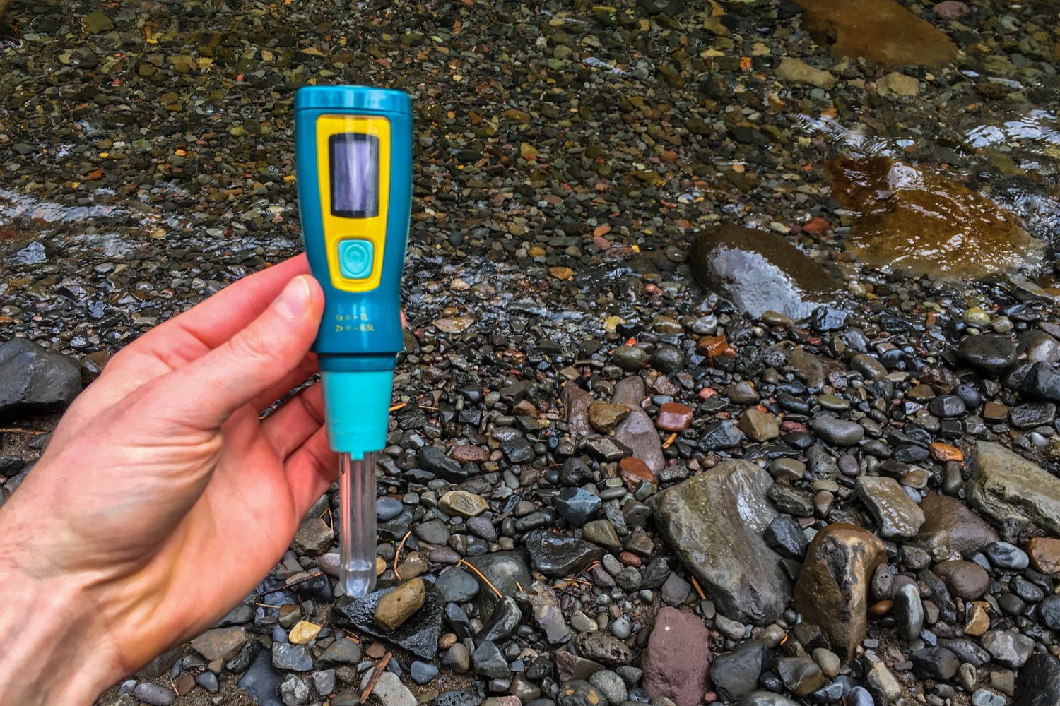 Closeup of the SteriPEN Ultra water purifier in front of a rocky creekbed