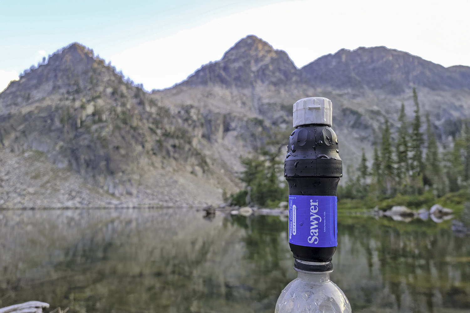 Closeup of the Sawyer Squeeze water filter in front of an alpine lake