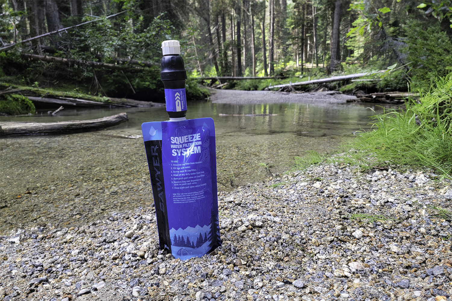 Closeup of the Sawyer Squeeze water filter by a granite-lined creek