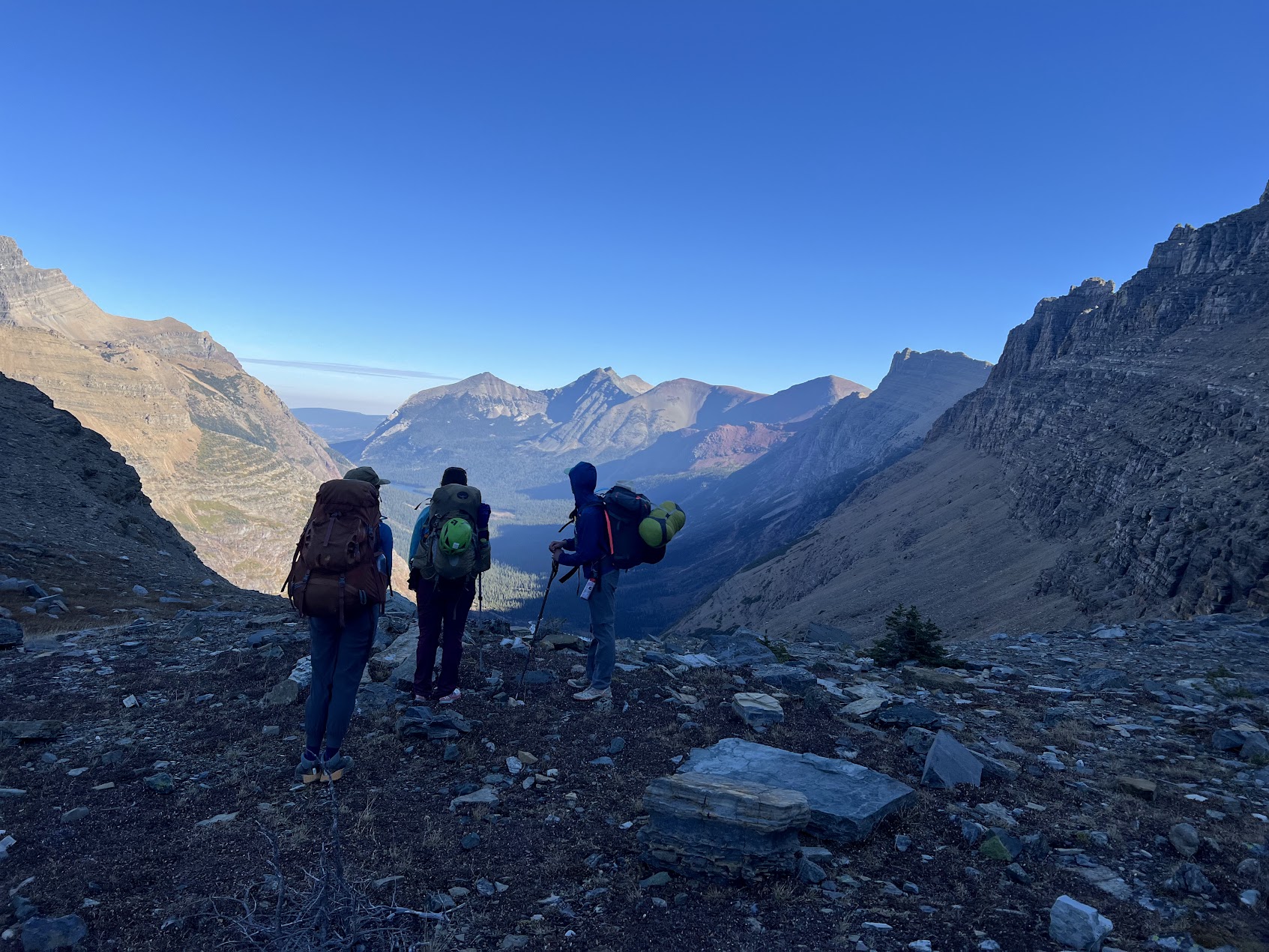 three backpackers overlooking a valley in glacier national park