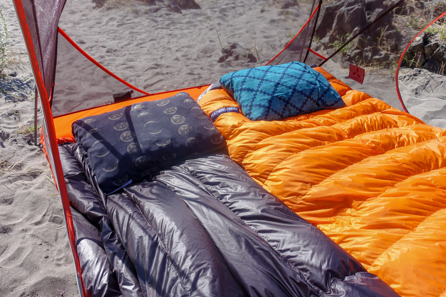 Close-up shot of two sleeping bags setup with pillows inside a tent with no fly on.