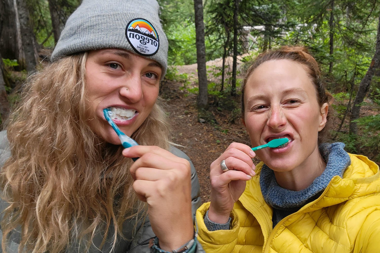 Two women brushing their teeth on a backpacking trip