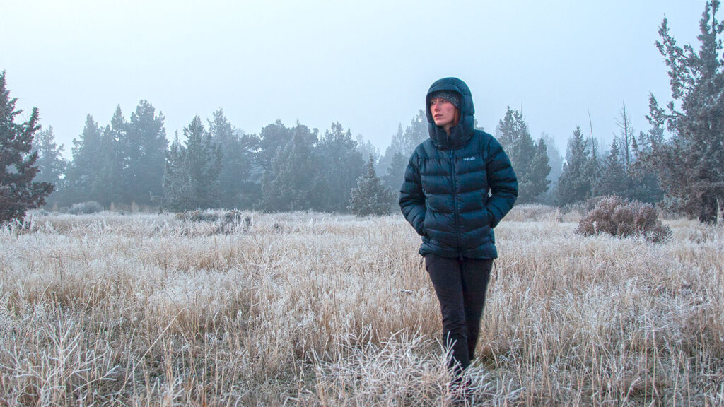 A hiker walking through a freezing field in the Rab Neutrino Pro down jacket