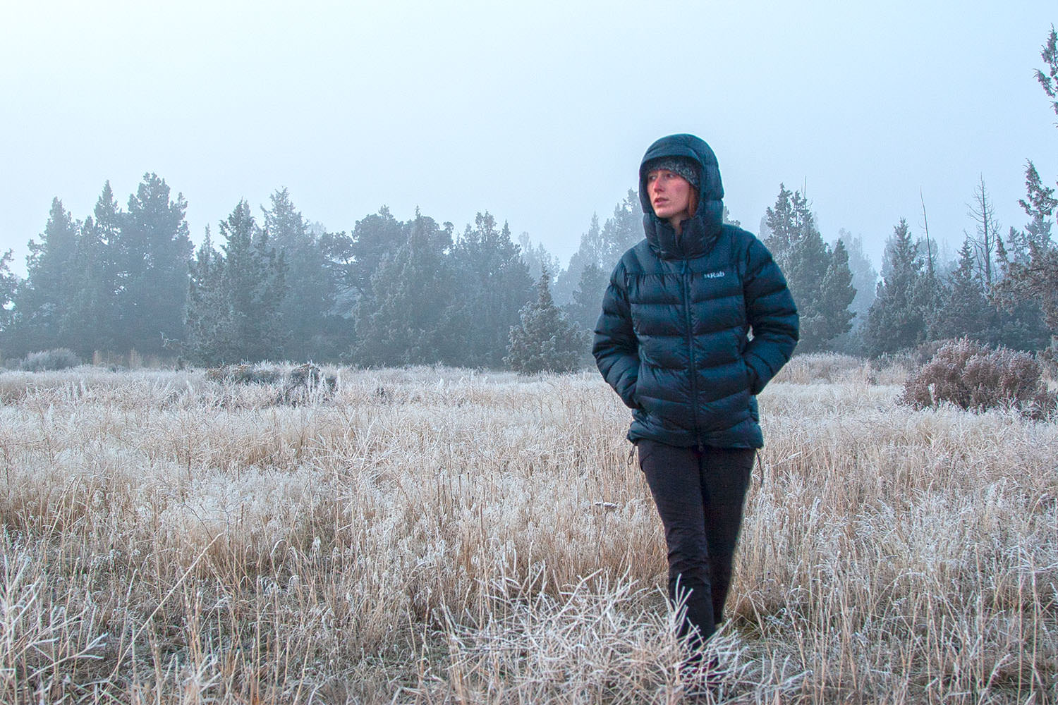 A hiker walking through a freezing field in the Rab Neutrino Pro down jacket