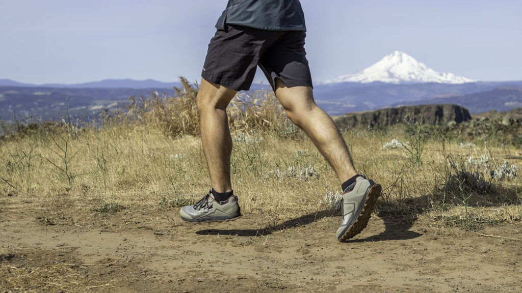 Waist-down view of a runner wearing the Altra Lone Peak trail running shoes with a view of Mt. Hood in the background