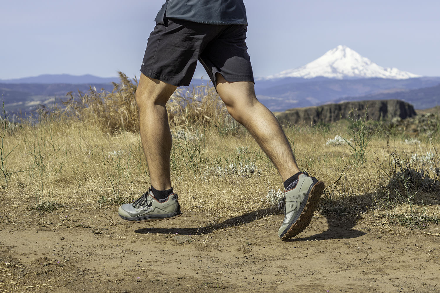 Waist-down view of a runner wearing the Altra Lone Peak trail running shoes with a view of Mt. Hood in the background