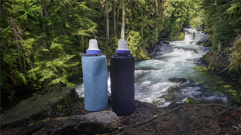 Blue and black HydraPak Flux water bottles fitted with Katadyn BeFree Water Filters in front of the clear-blue McKenzie River