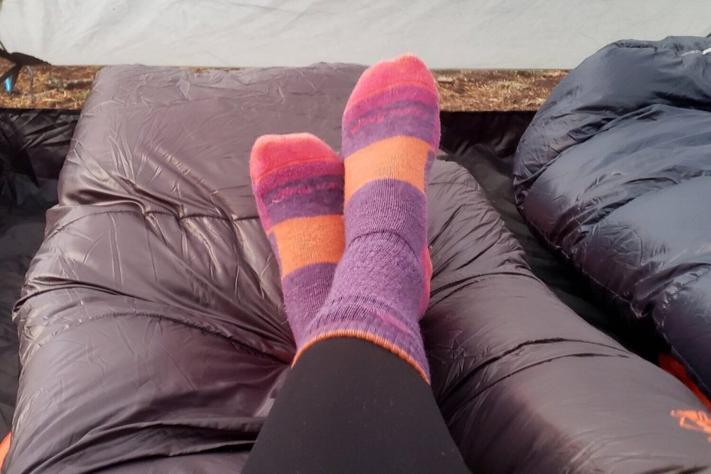 hiker's feet wearing socks resting atop their sleeping bag