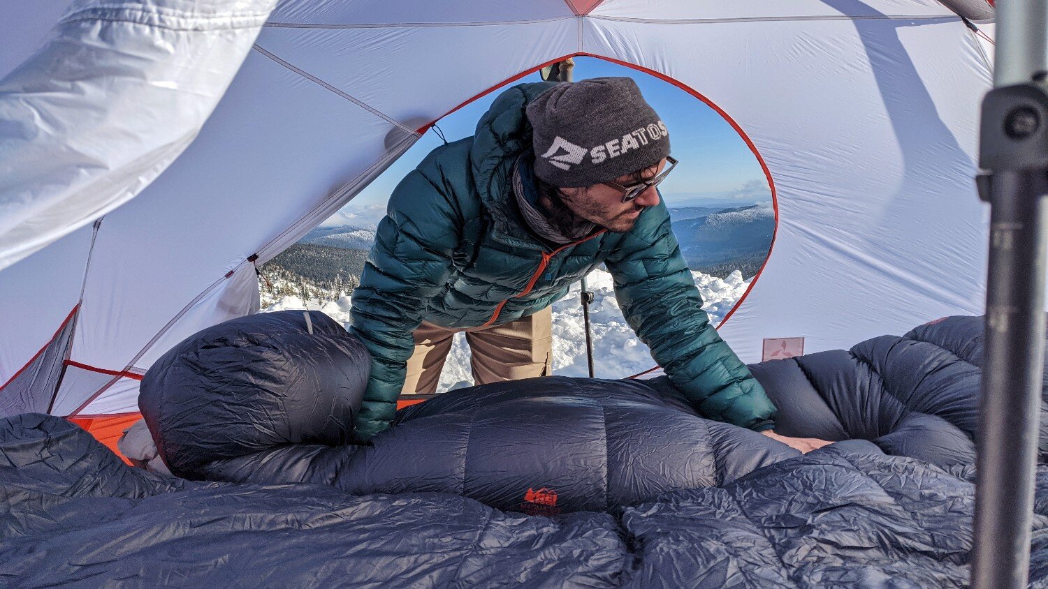 A hiker situating a sleeping bag in a 4-season tent on a winter camping trip.