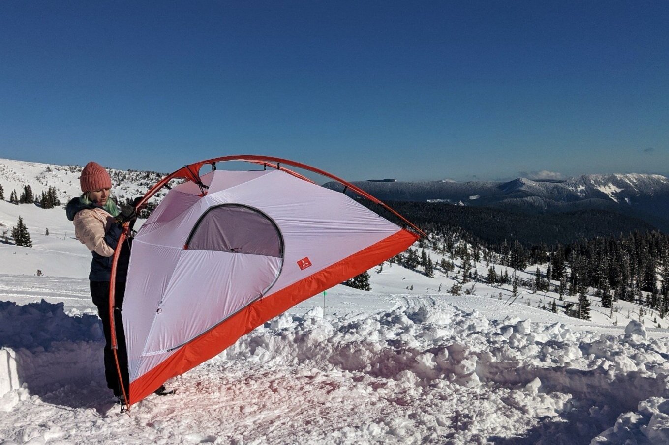 A hiker placing the Slingfin Crossbow 4-season tent in a dug out snow campsite