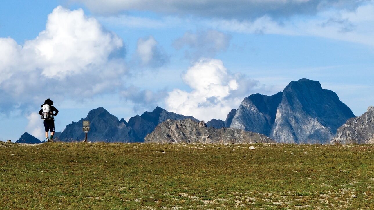 A+hiker+looking+at+a+big+view+of+the+Grand+Teton+Mountains