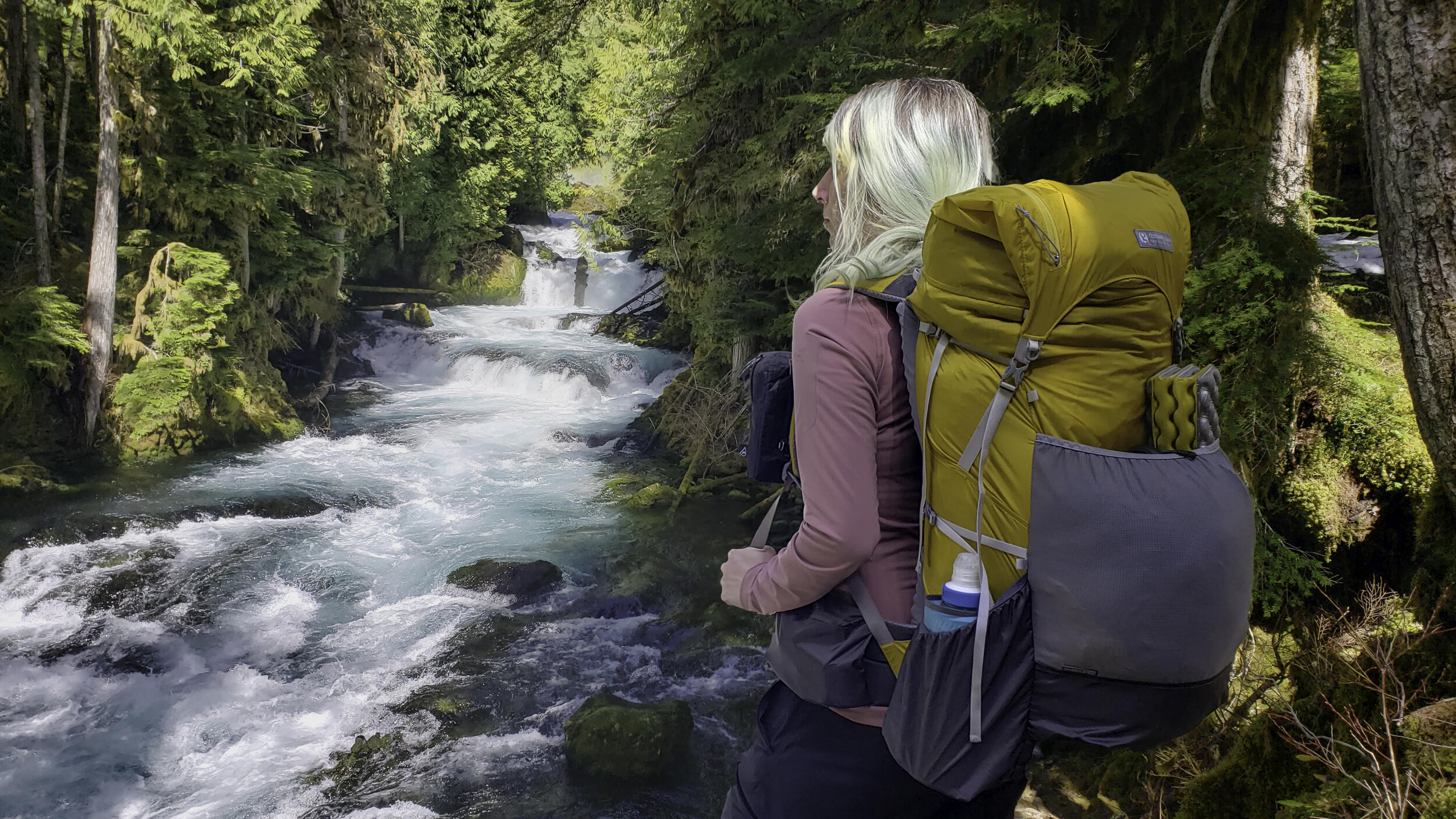 A hiker wearing the Gossamer Gear Gorilla 50 backpack in front of a river view
