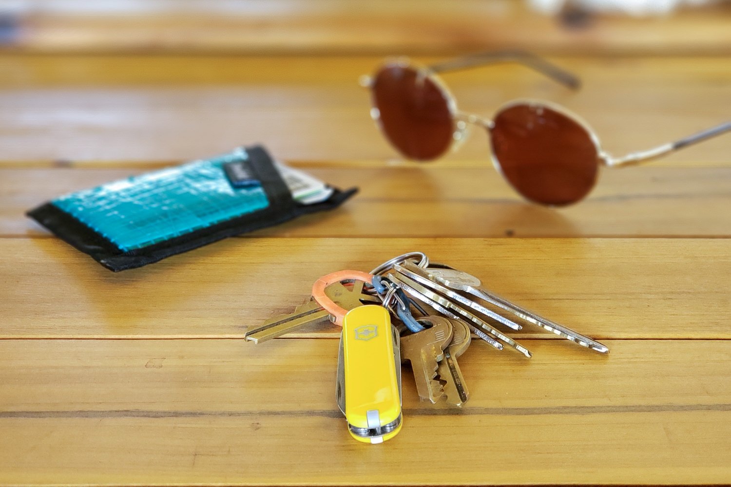 The Swiss Army Classic multitool sitting on a table next to a wallet and sunglasses
