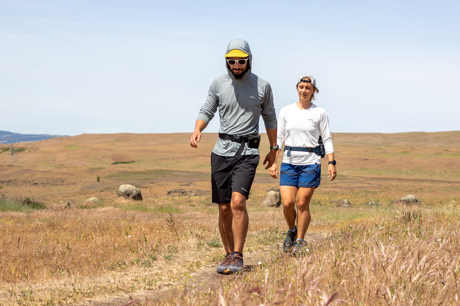 Two hikers walking on a trail wearing sun shirts