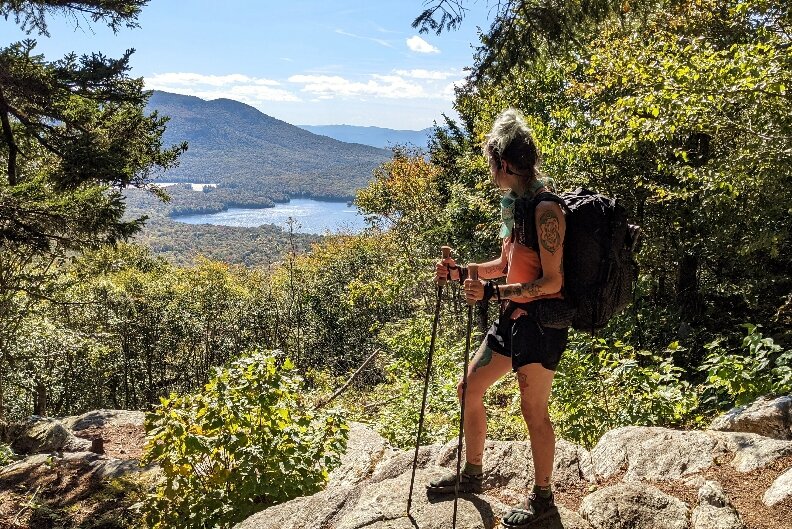 A hiker holding the Gossamer Gear LT5 trekking poles looking off at a distant view