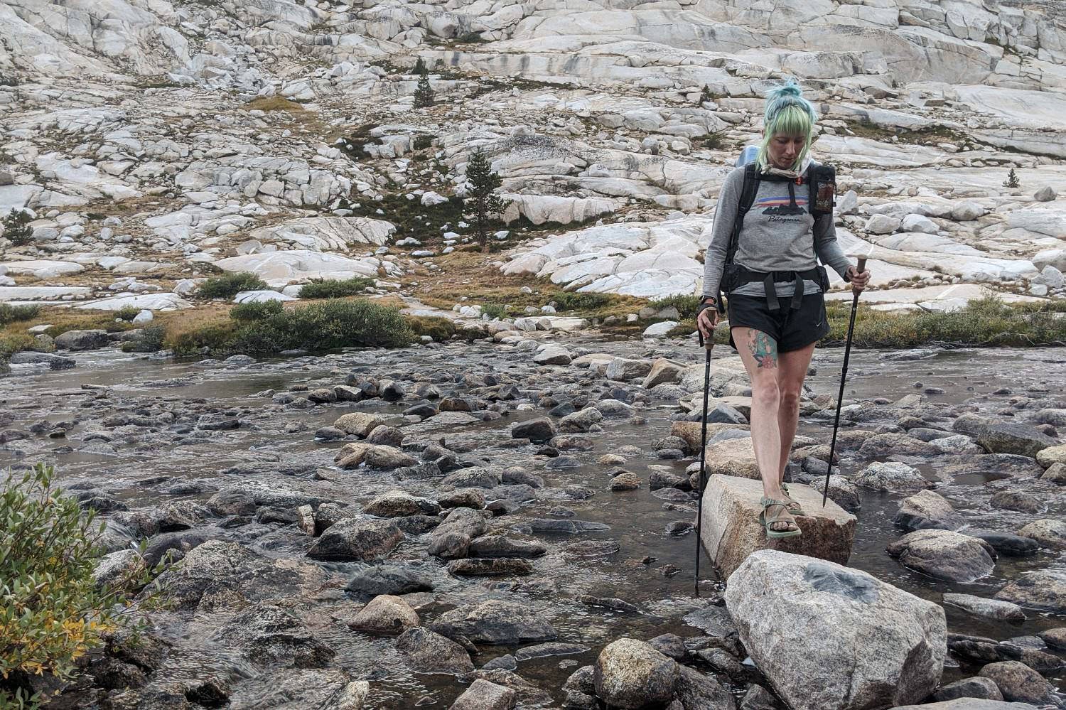 A hiker holding the Gossamer Gear LT5 trekking poles while crossing a river