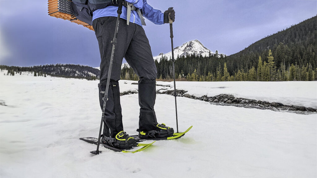 A snowshoer hiking along a winter creek in the Tubbs Flex VRT snowshoes