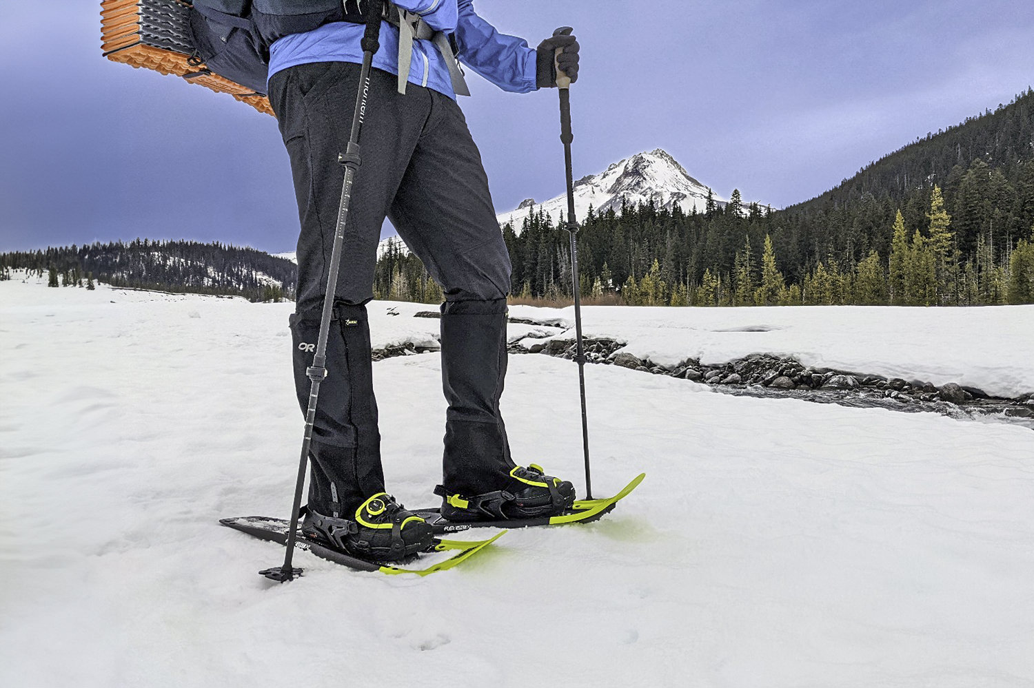 A snowshoer hiking along a winter creek in the Tubbs Flex VRT snowshoes