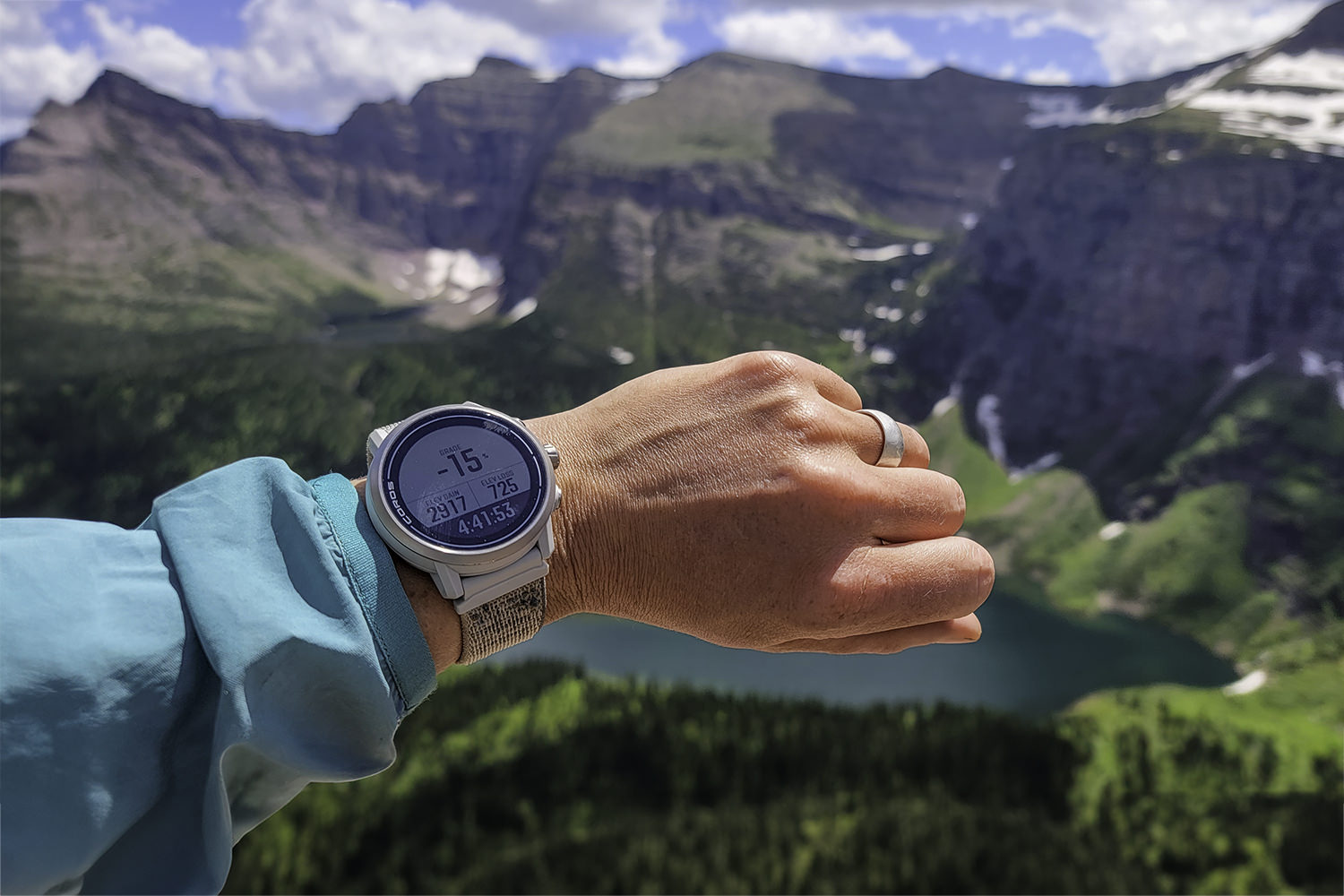 Closeup of the Coros Apex 2 GPS Watch on a backpacker's wrist with steep mountains in the background