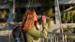 A red-headed woman drinking out of the Yomious 20 oz. water bottle at the airport