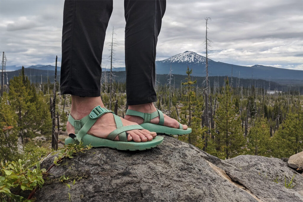 A hiker posing on a rock in the women's Chaco Z/1 Classic Sandals
