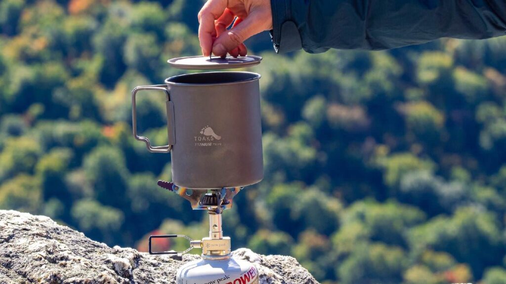 Closeup of a backpacker peaking under the lid of the TOAKS Titanium 750ML backpacking pot