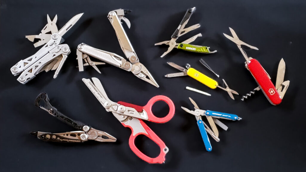 Top-down view of a variety of colorful multitools on a black background