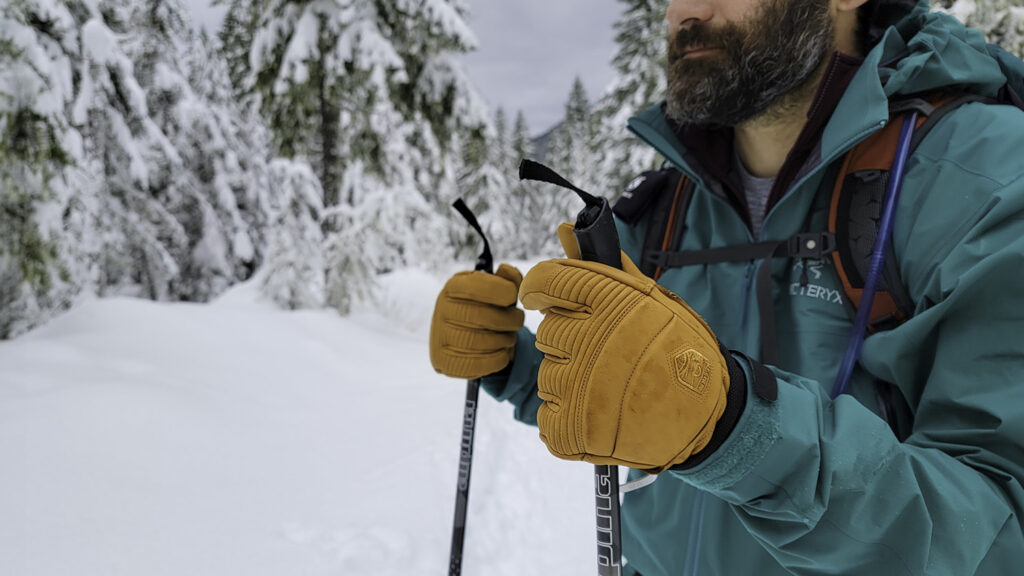 Closeup of a bearded man wearing the Hestra Fall Line gloves on a snowshoeing trail