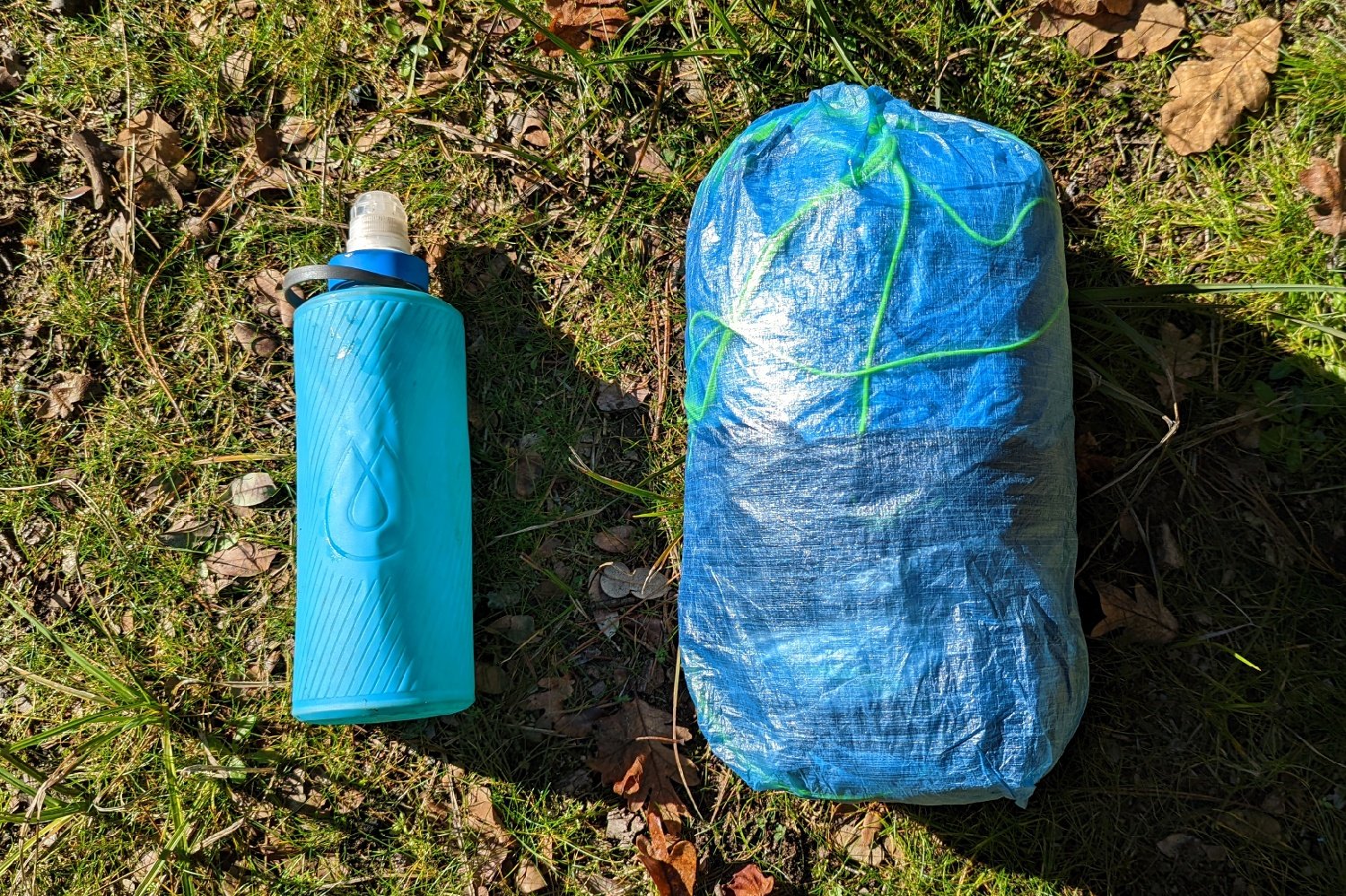 The Zpacks Plex Solo tent in a stuff sack next to a one liter water bottle