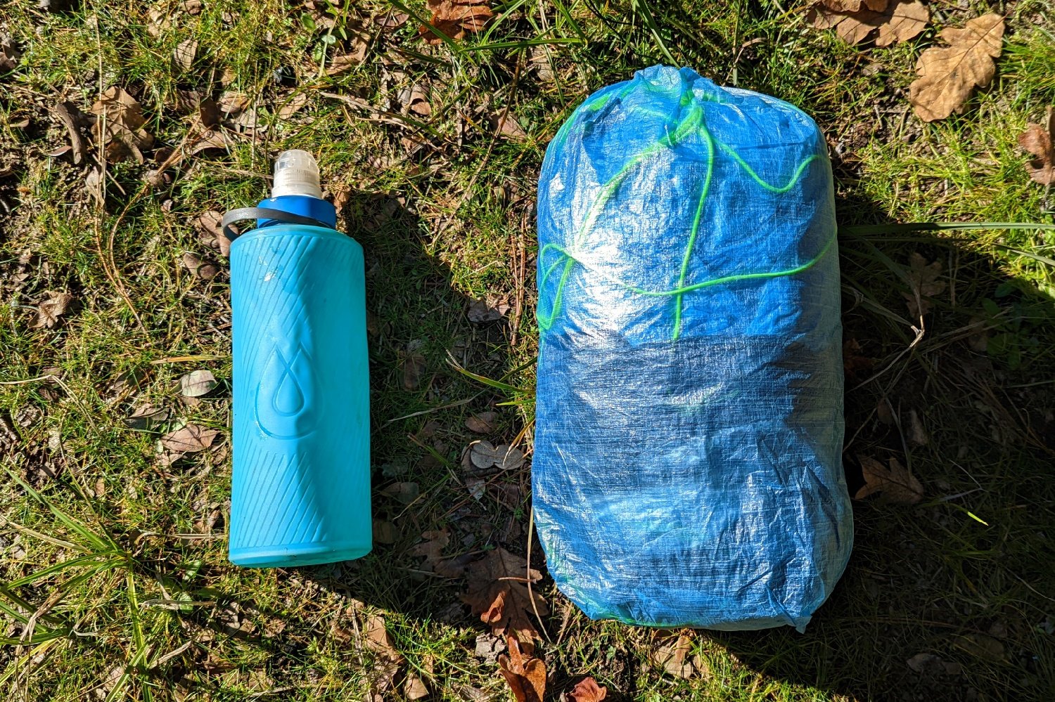the zpacks plex solo tent packed in a compression sack displayed next to a one liter water bottle to compare size