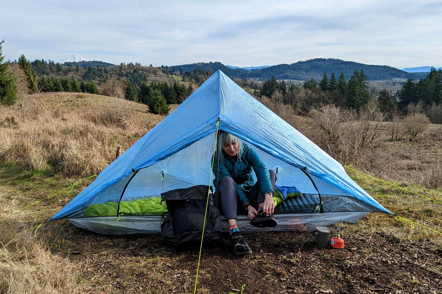 A hiker sitting in the doorway of the Zpacks Plex Solo tent putting their shoes on