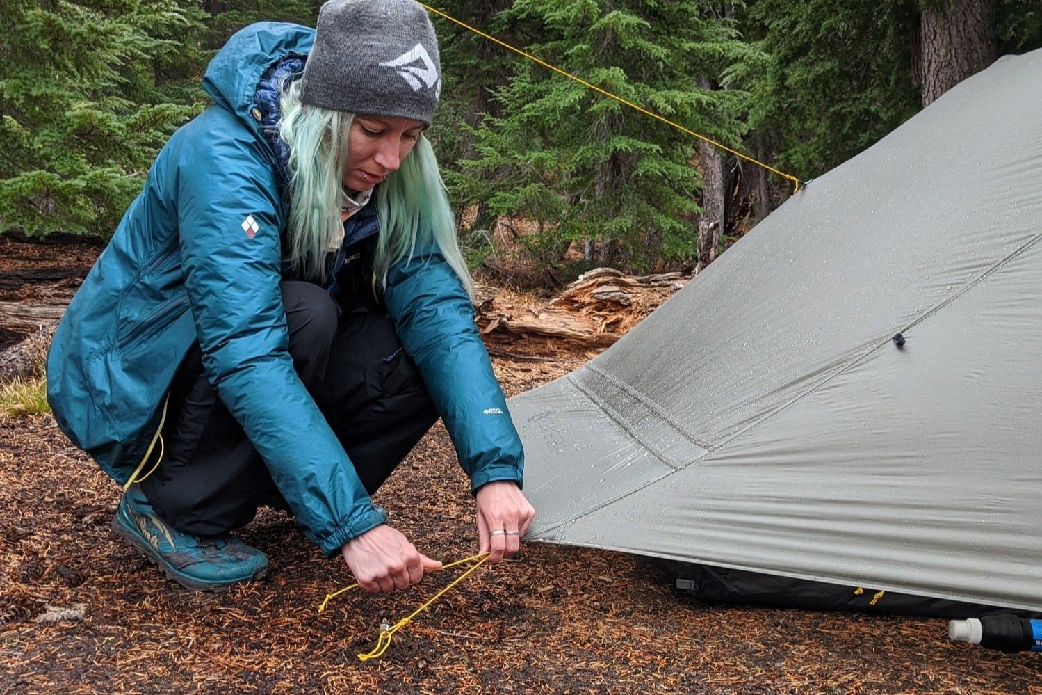 A hiker adjusting the tension of a corner guyline on the Gossamer Gear The Two