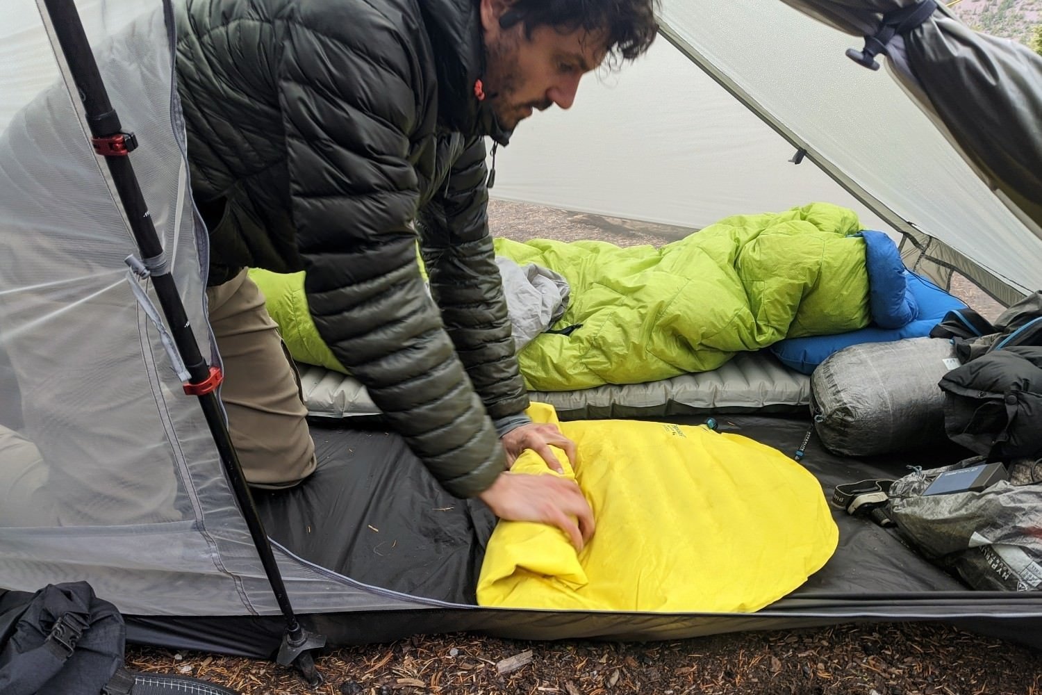 A hiker rolling up a sleeping bag inside the Gossamer Gear The Two