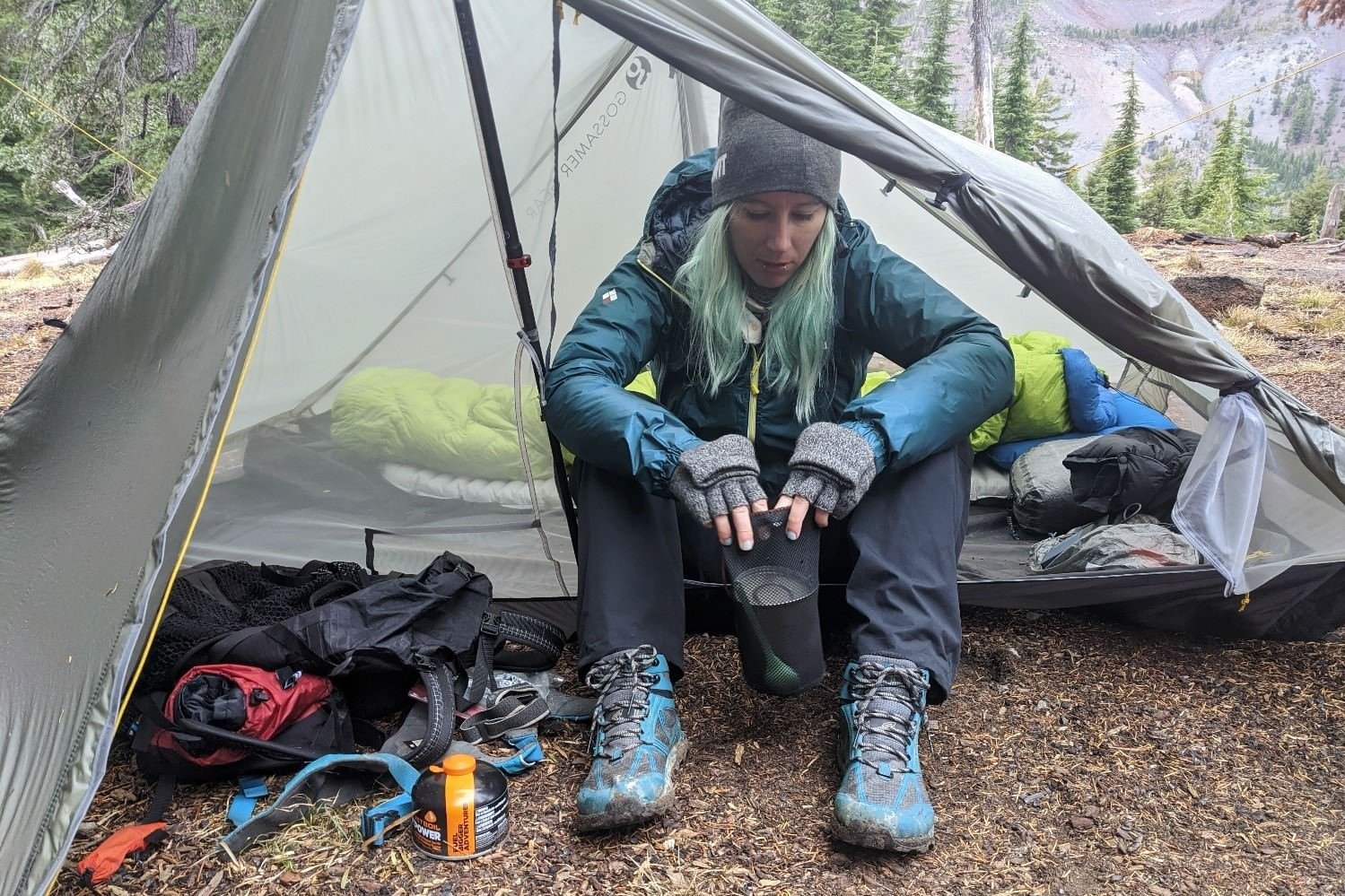A hiker sitting in the doorway of the Gossamer Gear The Two with their gear in the vestibule