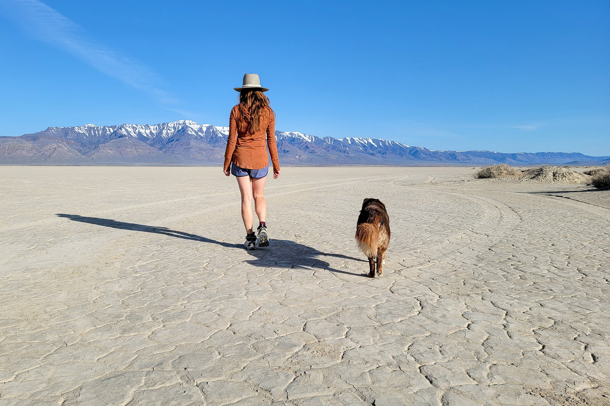 A woman and her dog in from of the Steens Mountains in the Alvord Desert