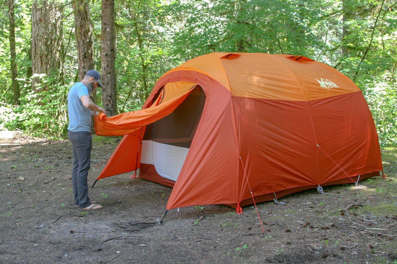 A camper rolling up the door on the REI Kingdom 6 tent
