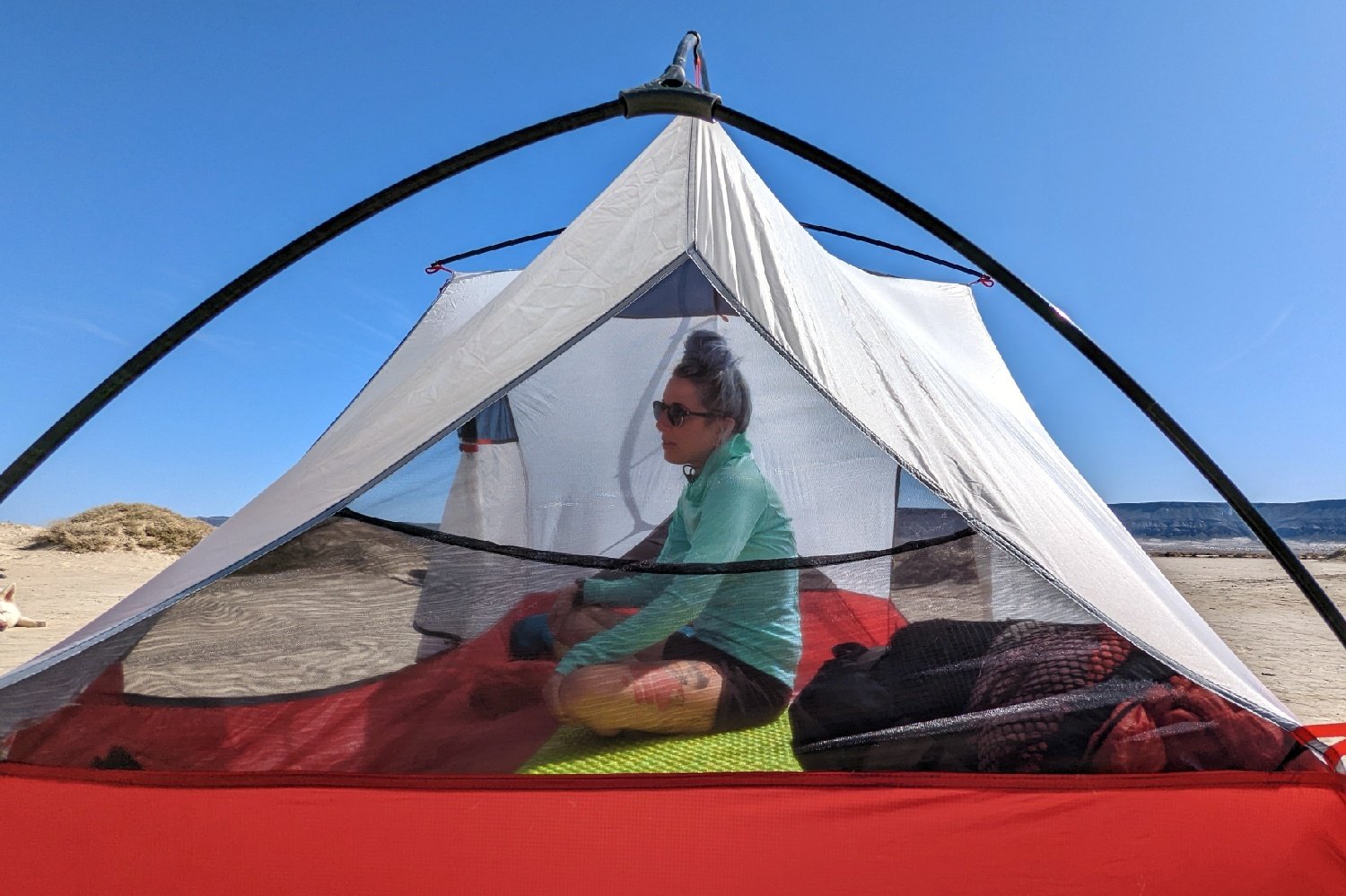 Close up of a tent pitched without the fly, showing a woman sitting up inside with plenty of headroom.