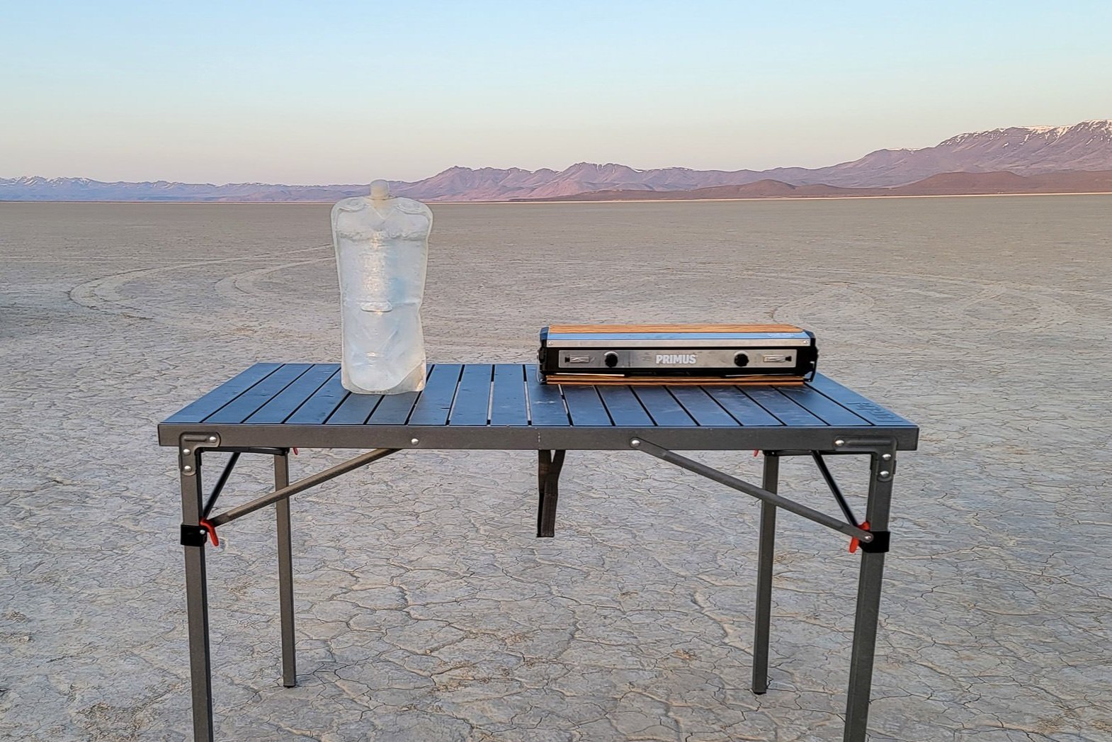 A full platypus pouch sitting on a table next to a camp stove in the desert