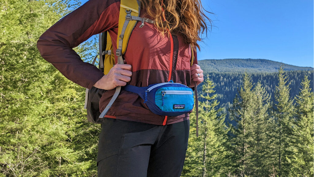 Closeup of a female hiker wearing the Patagonia Black Hole Mini fanny pack with a backpack