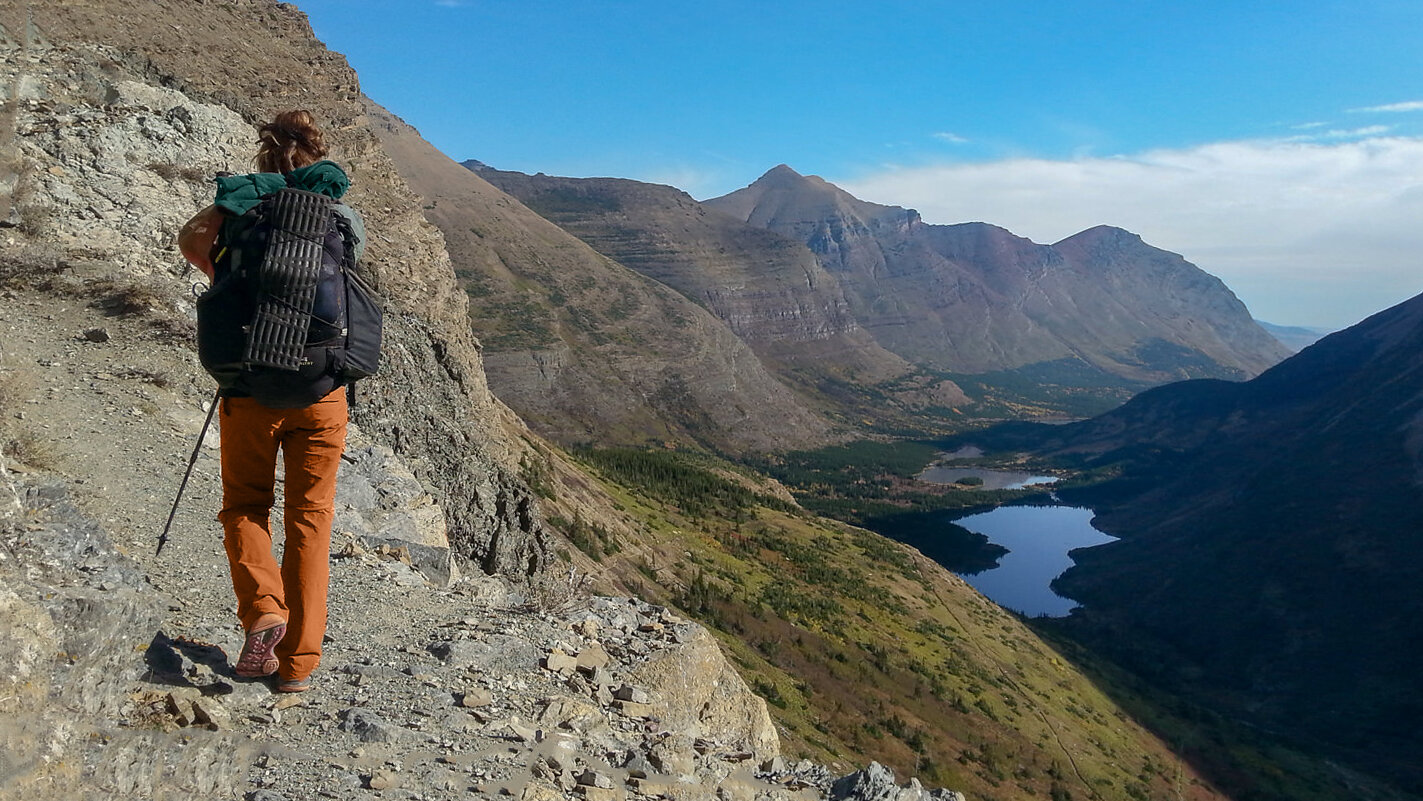 a backpacker hiking on a ridge overlooking an epic view of Glacier National Park
