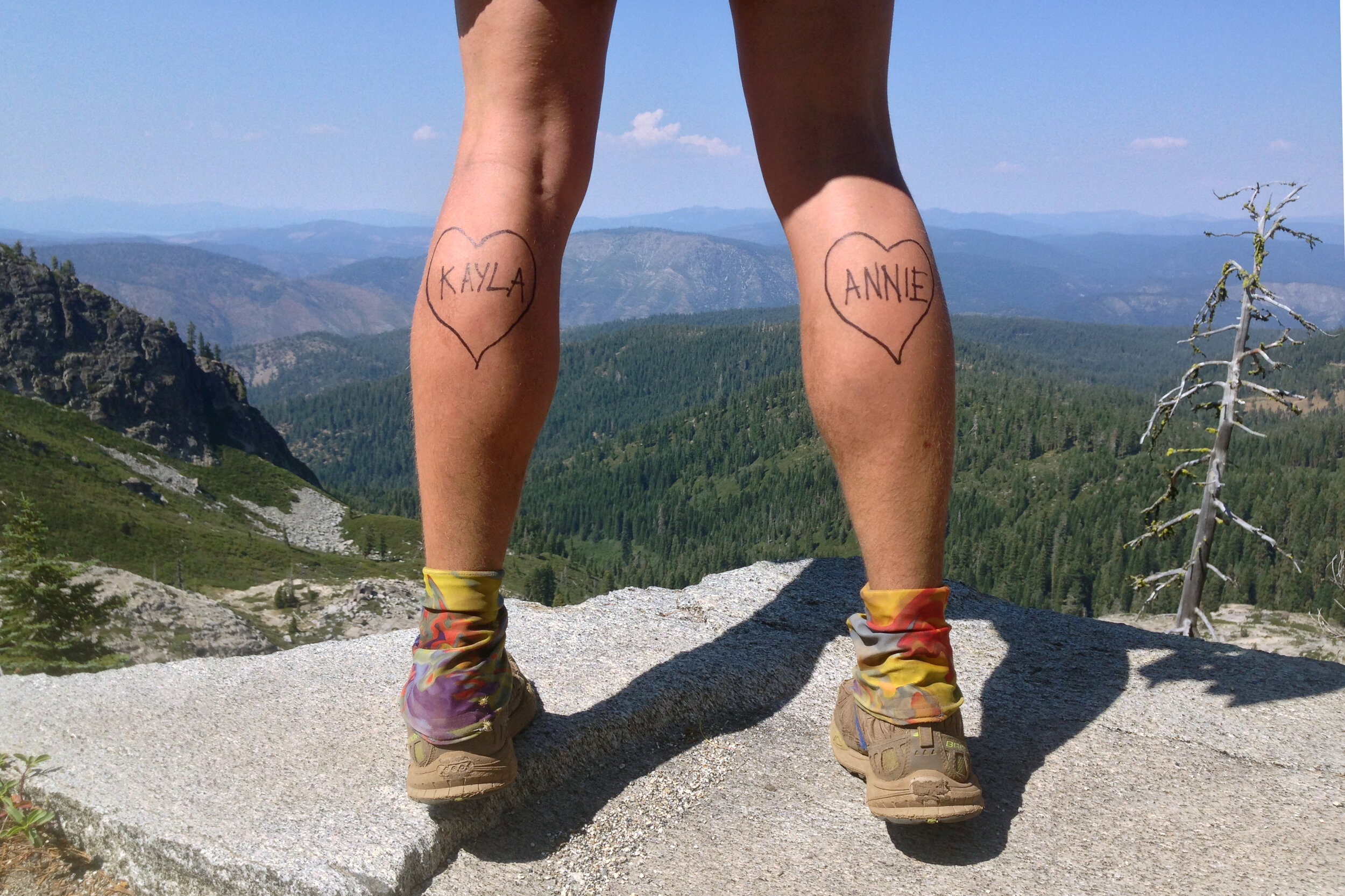 a backpacker flexes for a photo to send home with fake tattoos of the names of loved ones on her calves