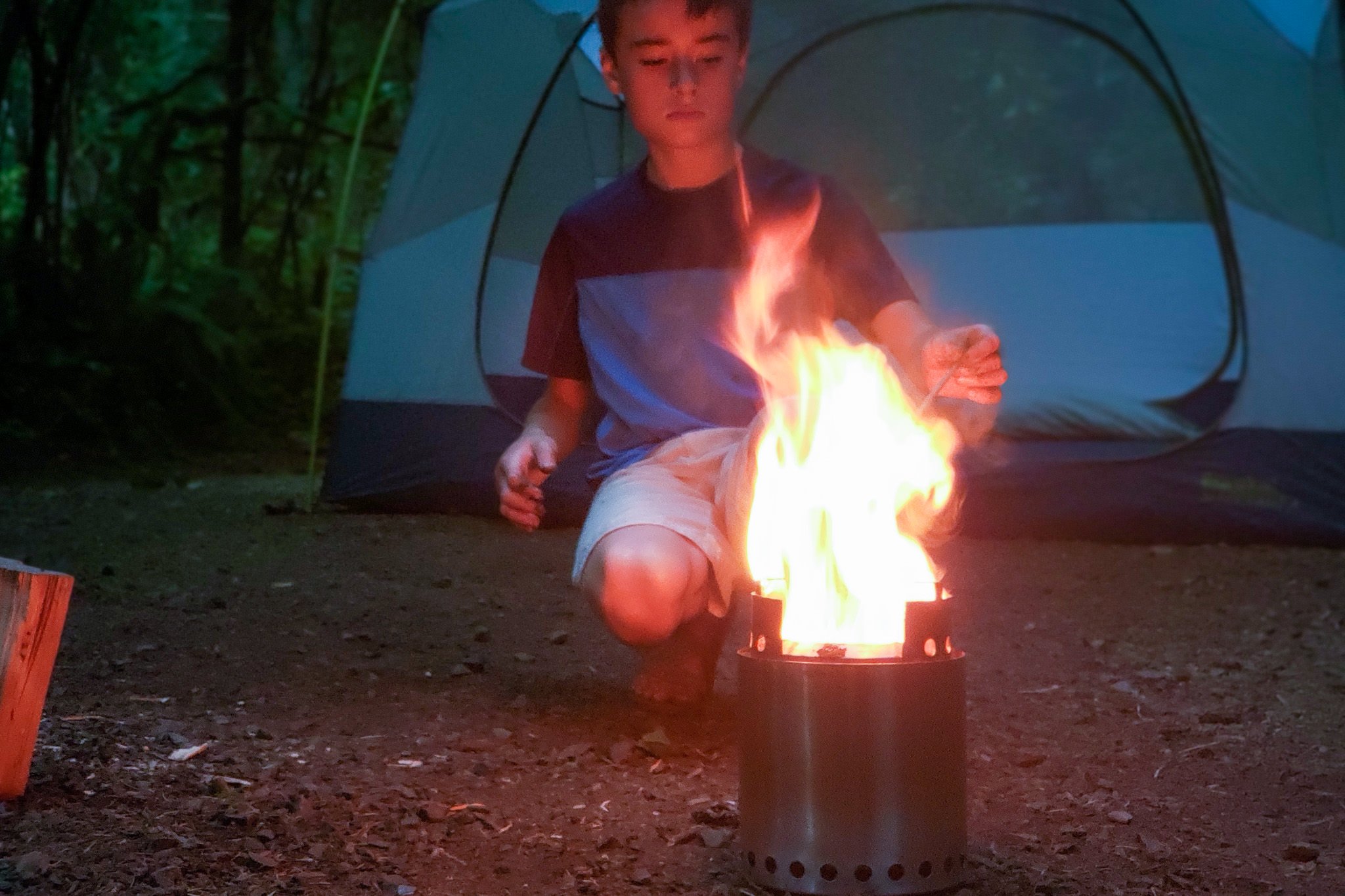 A person adding a twig to a fire in the Solo Stove Campfire Stove