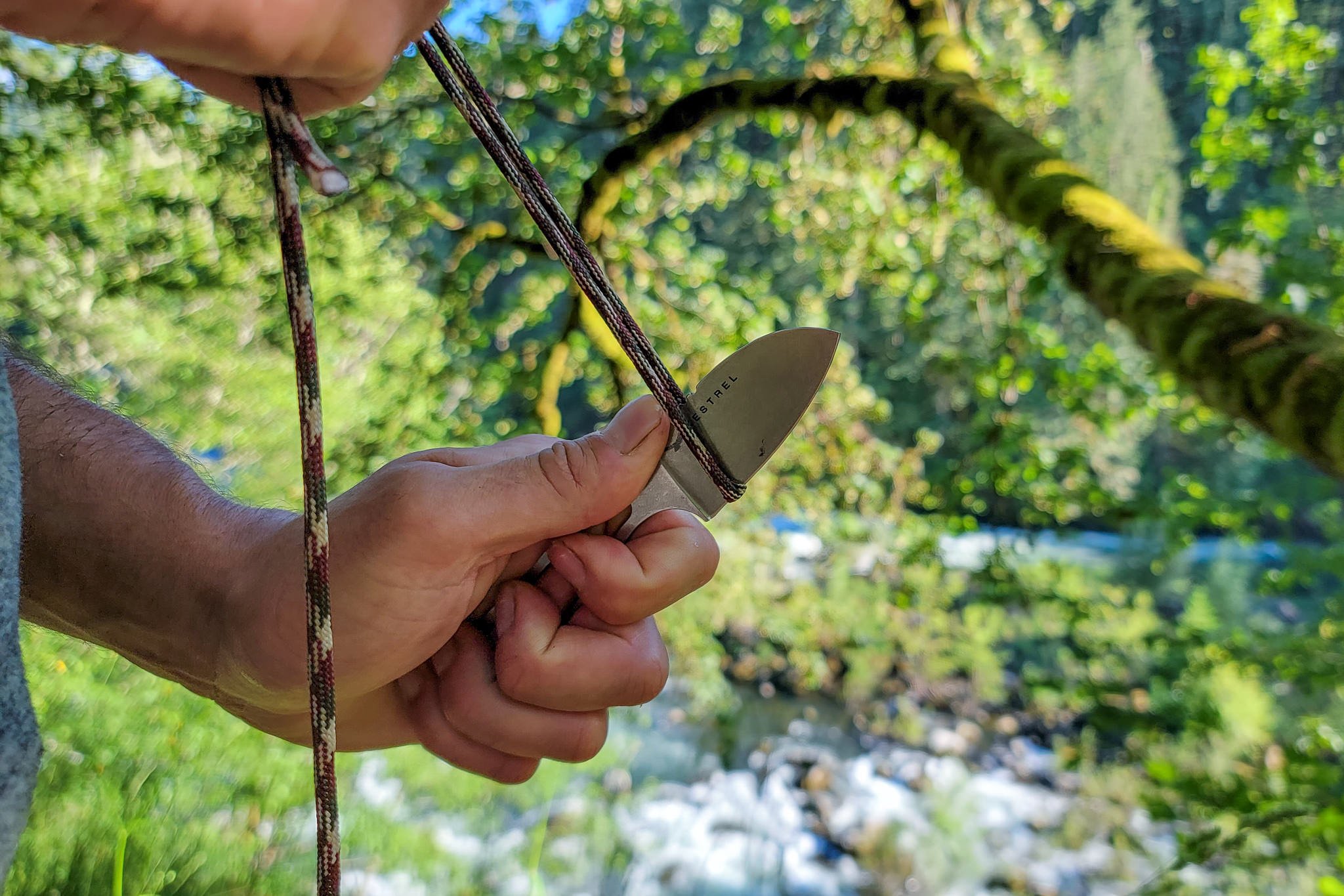 Closeup of a backpacker cutting paracord with the ULA Alpha Knife